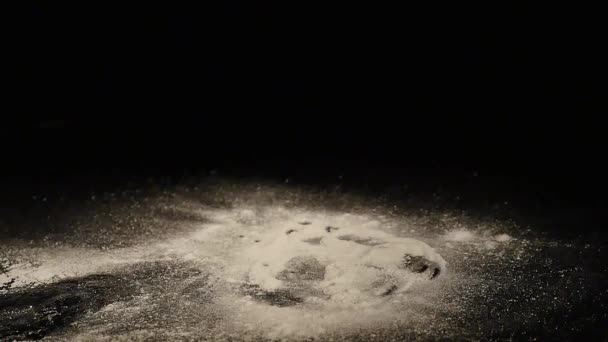 Una dona con un polvo de azúcar cae sobre un escritorio negro — Vídeo de stock
