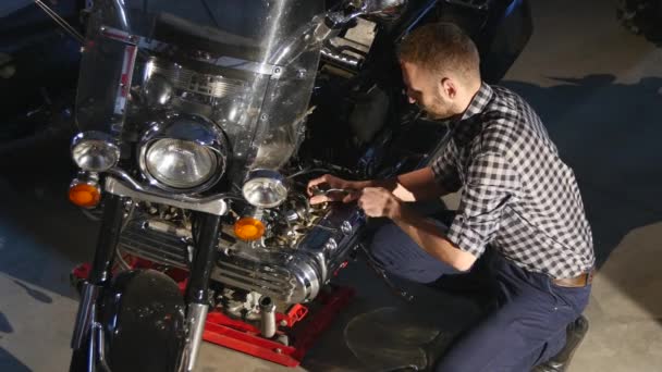 Jovem sério reparando sua moto na garagem — Vídeo de Stock