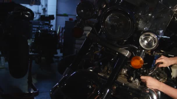 Serious young man repairing his motorcycle in garage — Stock Video