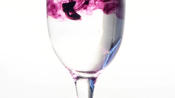 Tinta de cor que flui em vidro de água no fundo branco — Vídeo de Stock