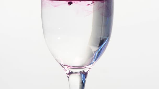 Encre violette tombant dans un verre d'eau plate — Video