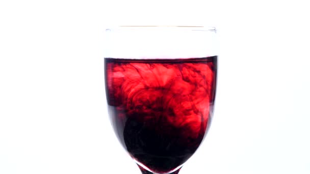 Encre rouge foncé tombant dans un verre d'eau — Video