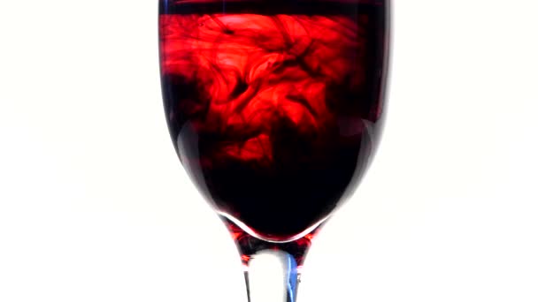 Tinta roja oscura cayendo en un vaso de agua — Vídeos de Stock