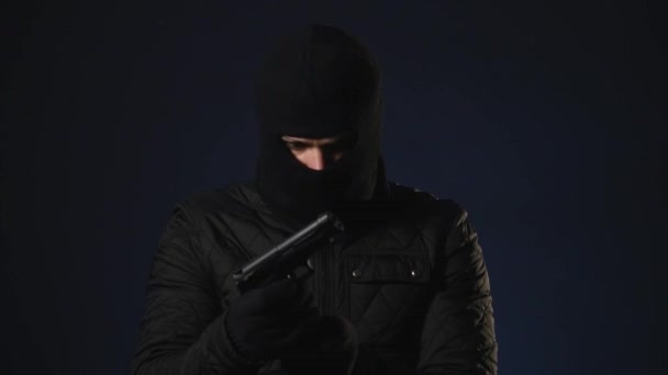Un hombre enmascarado toma un arma en la mano. Concepto de terrorismo — Vídeos de Stock