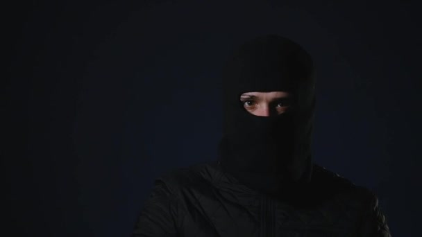 En maskerad man tar en pistol i handen. Terrorism-konceptet — Stockvideo
