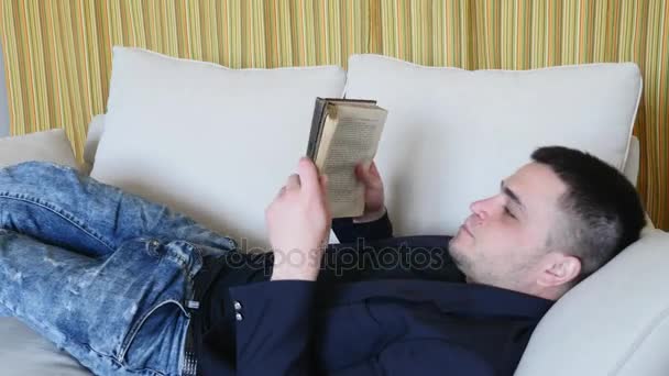 Hombre leyendo un libro acostado en el sofá y los sueños — Vídeo de stock