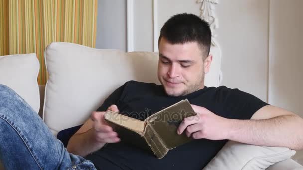 Hombre leyendo un libro acostado en el sofá y los sueños — Vídeo de stock