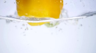 Beyaz arka plan üzerinde suya düşen biber