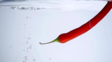 suya düşen beyaz zemin üzerine kırmızı biber