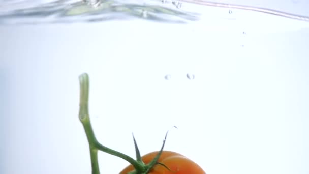 Primer plano de tomate fresco y pimienta cayendo en agua clara con gran salpicadura aislada sobre fondo blanco. Alimentación saludable — Vídeos de Stock