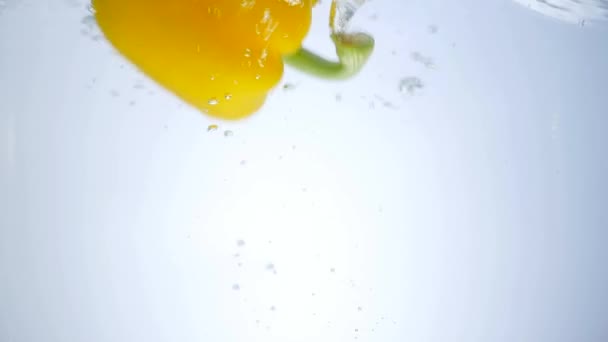 Gele peper vallen in water — Stockvideo