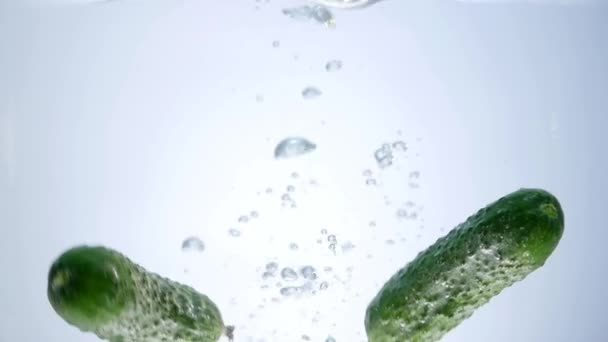 Pepino verde caído en el agua aislado sobre fondo blanco — Vídeo de stock