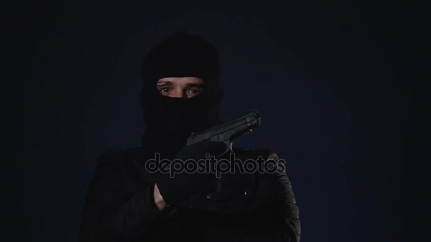 Человек в маске берет в руки пистолет. Концепция терроризма — стоковое видео