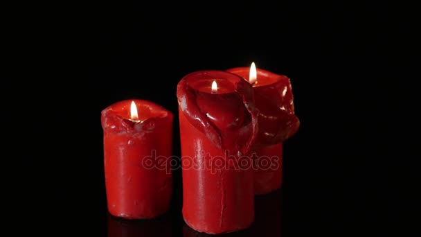 Cerca de 3 velas rojas encendidas girando alrededor del fondo negro — Vídeos de Stock