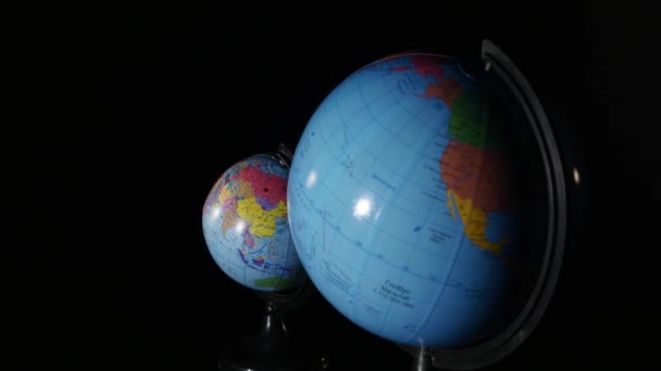 Kleine en grote een wereldbol draaien op zwarte achtergrond — Stockvideo