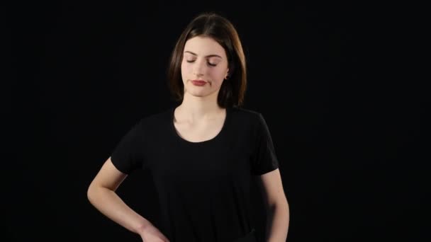 Hermosa joven está usando un teléfono inteligente y sonriendo, de pie sobre un fondo oscuro — Vídeos de Stock