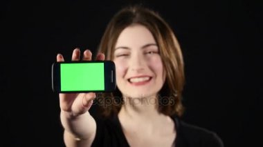 Cep telefonu üzerinde odaklanın. Eller genç kadın üzerinde yeşil arka plan izole ve ekranda gösteren boş smartphone ekran gösterilen
