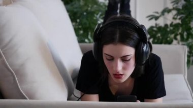Güzel çekici genç kadın kanepede yatan ve müzik smartphone ile