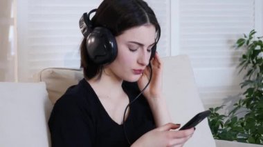 Kanepede oturan ve müzik güzel çekici genç kadın