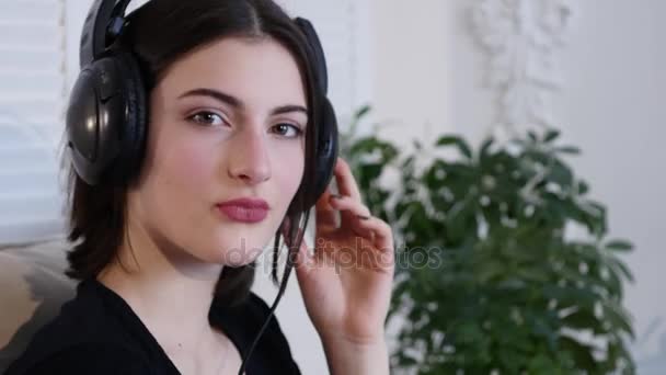 Mujer cantando y escuchando música en auriculares mirando a la cámara — Vídeo de stock