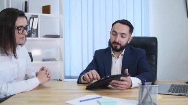 iş adamları oturup birlikte dijital tablet üzerinde verilere bakarak Toplantı