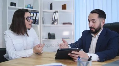 iş adamları oturup birlikte dijital tablet üzerinde verilere bakarak Toplantı