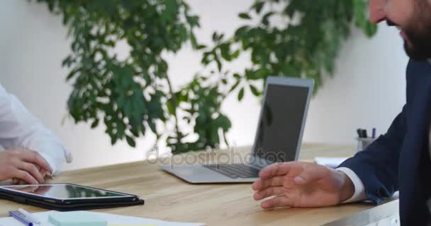 Gli imprenditori si siedono e tengono un incontro informale guardando insieme i dati sul tablet digitale — Video Stock