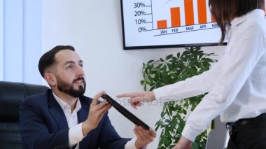 Dijital tablet bir ofiste olan bir kadın için bir şeyler açıklamaya iş adamı