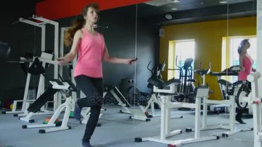 İp atlama ve sağlıklı rutin ile spor salonunda fitness üzerinde çalışan genç atletik kadın
