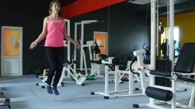 İp atlama ve sağlıklı rutin ile spor salonunda fitness üzerinde çalışan genç atletik kadın