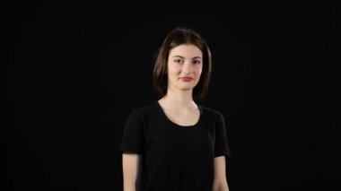 Sevimli genç bir beyaz kadın gülümsüyor ve kırpmak siyah bir arka plan üzerinde