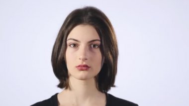 Sevimli genç bir beyaz kadın beyaz bir arka plan üzerinde üzgün bir yüz yapar