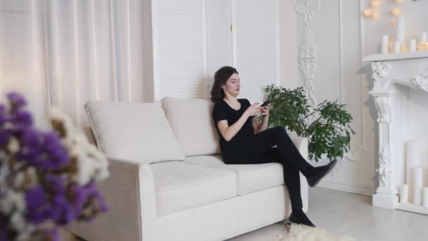 Belle jeune femme parlant sur téléphone portable à la maison. Femme détendue au téléphone portable assis sur le canapé — Video