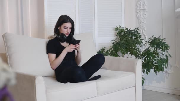 Young woman listen to music sitting on sofa at home 4K — Stock Video