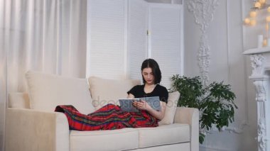 Çekici genç kadın kanepede yatan ve kitap okuma