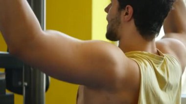 Spor salonunda makine üzerinde egzersiz yapan formda bir adam.