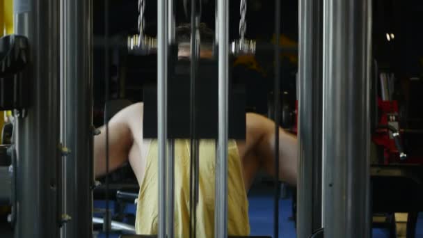 Hombre en forma haciendo ejercicio en el gimnasio en una máquina — Vídeos de Stock