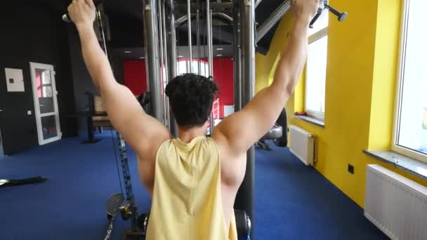 Hombre en forma haciendo ejercicio en el gimnasio en una máquina — Vídeos de Stock