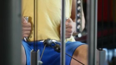 Spor salonunda makine üzerinde egzersiz yapan formda bir adam.