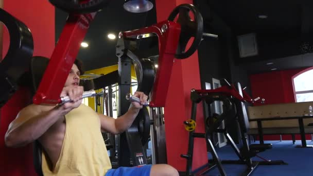 Hombre deportivo guapo está haciendo ejercicio en el centro de gimnasia — Vídeos de Stock