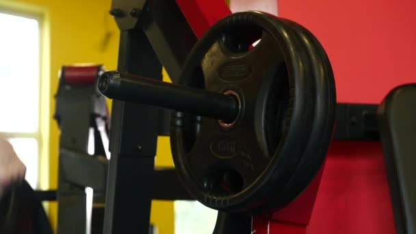 Overgang schot van vastberaden gespierde man zware platen zetten barbell en tillen in de sportschool. Sportieve jongeman voorbereiden van gewichtheffen in een crossfit fitnessruimte. Voorbereiding — Stockvideo