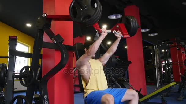 Hombre deportivo guapo está haciendo ejercicio en el centro de gimnasia — Vídeos de Stock