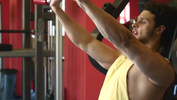 Hombre deportivo guapo está haciendo ejercicio en el centro de gimnasia — Vídeo de stock