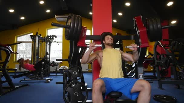 Bonito homem desportivo está se exercitando no centro de fitness — Vídeo de Stock