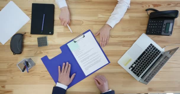 Empresário assinando um contrato com desktop e papelada em segundo plano, vista superior — Vídeo de Stock