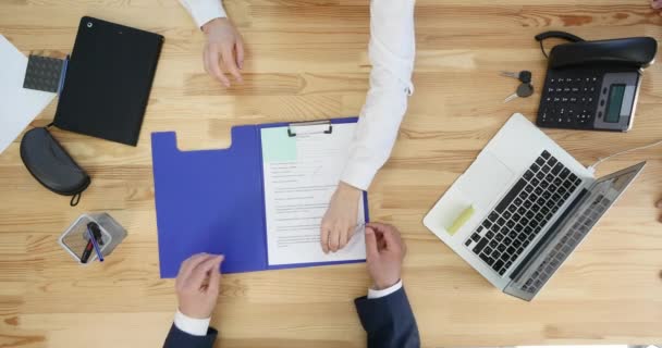 Geschäftsmann unterschreibt Vertrag mit Desktop und Papierkram im Hintergrund, Draufsicht — Stockvideo