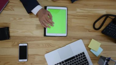 Dizüstü ve tablet ve akıllı telefon ile çalışan adam Üstten Görünüm tablo boş yeşil ekran dokunmatik