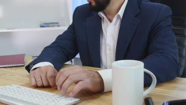 Ein zufriedener Geschäftsmann sitzt in seinem Büro und arbeitet an seinem Computer — Stockvideo