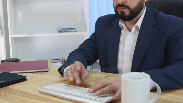 Lächelnder Geschäftsmann, der in seinem Büro zum Telefon greift — Stockvideo