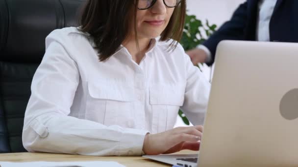 A menina bonita consulta com homens sobre o projeto no computador portátil no escritório. Ele mostra um dedo na tela que você precisa corrigir. O conceito de trabalho em equipe no co-trabalho — Vídeo de Stock